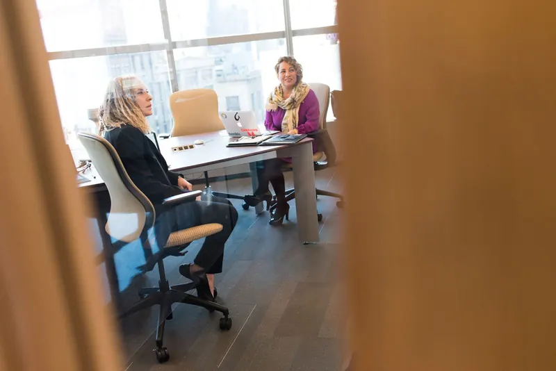 Two professionals in conversation around a meeting table